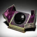 A 1926 Baccarat for Isabey “Tresor Cache” presentation of Lys black crystal perfume bottle and stopper as a faceted jewel with cord seal, label and tooled leather box sold for $56,250 at an auction held July 11 by Perfume Bottles Auction in New York City