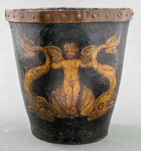 5. An example of an English paint decorated leather fire bucket with a metal band, 18th/19th century, showing nautical motifs of a winged cherub rising from a wave with a dolphin in each hand. This example is part of a New York City estate auction with an estimate of $400-$600, indicative of the current market for a good example with a whimsical theme.