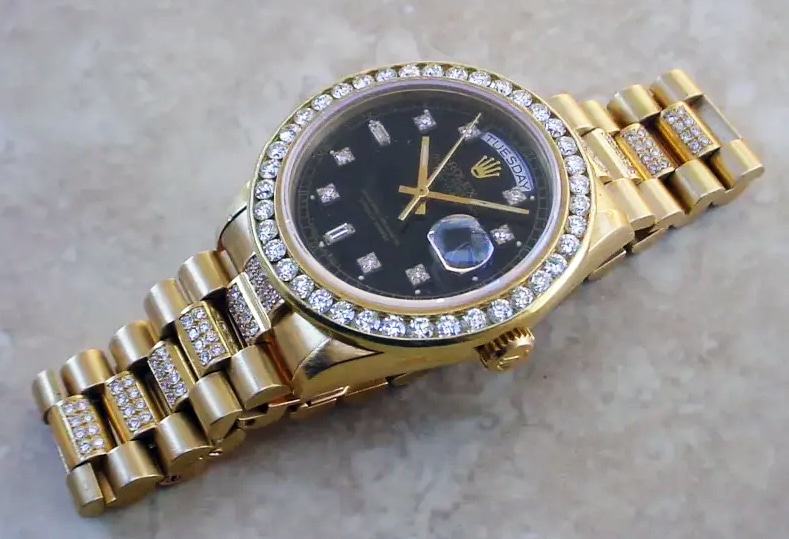 Rolex Day/Date 18038 with a black professionally redone dial set with aftermarket diamond hour markers. Custom-made 18kt gold heavy bezel, channel set with 2.8 carats of round brilliant-cut diamonds. Selling for $19,500 at Rubylane.com