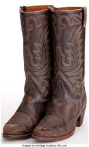 A John Wayne Pair of Lucchese cowboy boots likely from True Grit and Rooster Cogburn. Paramount, 1969 and Universal, 1975. Made of brown leather with tan-colored traditional stitching, inside stamped with maker’s logo. Further handwritten annotation in black felt tip ink reading “J.W.” Purposely distressed to look aged; believed to be worn by Wayne as “Rooster Cogburn” in early scenes of both or either film before the action got too rough. Sold for $6,562.50 at Heritage Auctions in 2016.