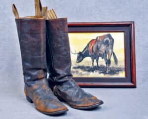 At left, original antique 1860 - 70s cowboy boots. These boots are the early classic two-piece arch front in a brown finish. Brown is far less common than the typical black boot. The sole in the arch is thin to allow a good feel of the stirrup – a feature on the first cattle drives after the war of northern aggression. These boots came out of a museum collection. The sole is stitched on the edge and glued to the inside of the sole. These boot soles were glued and stitched. Cowboys preferred glued or stitched for comfort in the stirrup. The use of pegs were more common for boots worn by sodbusters and infantry due to the harder wear when afoot.