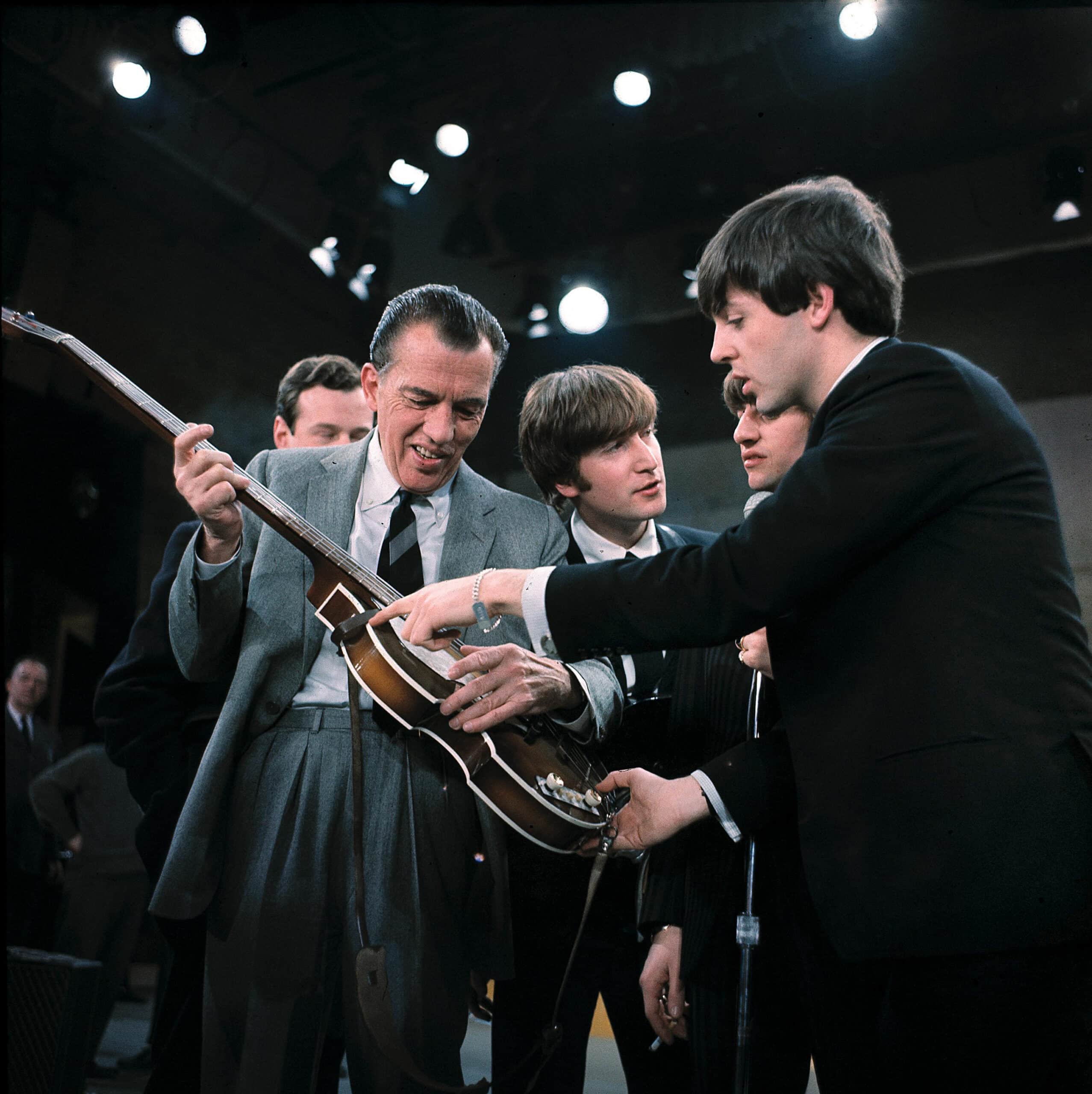 Paul McCartney, Ringo Starr, John Lennon with Ed Sullivan giving him a “guitar lesson” before appearing onstage at The Ed Sullivan Show, 1964.