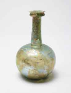 Roman glass round bottom vase with a weathered surface showing discoloration, cracking, and flaking