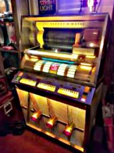 Now this … this beauty right here? This is not just a jukebox – it’s a time capsule. Pulled straight from the legendary Whispering Pines juke joint down in Mississippi. You can almost hear the blues still echoing off the chrome. Every nick, every smudge – it all tells a story. This machine didn’t just play records … it played memories.
