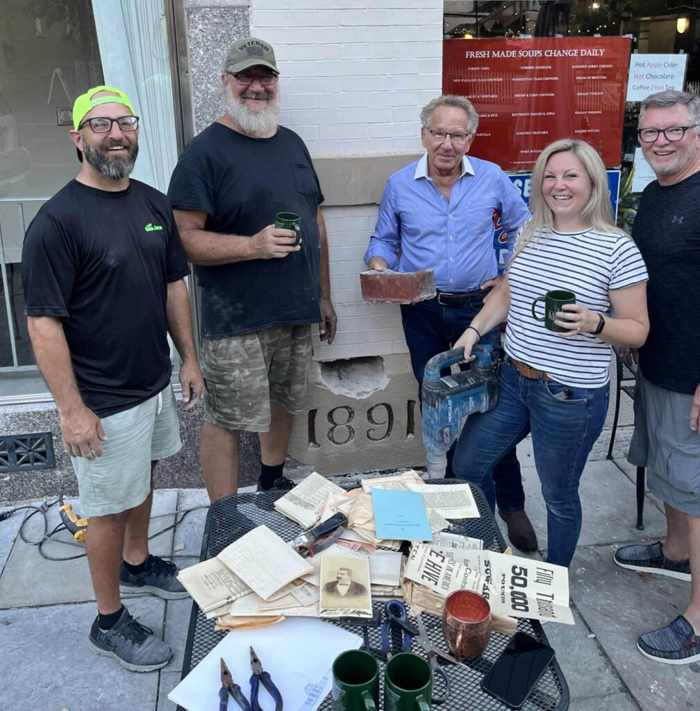 Left to right: Evan Blose, Jack Stanley, Lou Pektor, Lisa Pektor, and Randy Blose, showing the contents of the time capsule, and the dated cornerstone from where the capsule was retrieved.