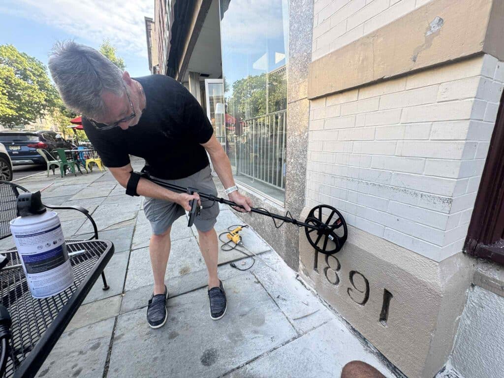 Randy Blose with metal detector, checking on the potential location of the box within the cornerstone.