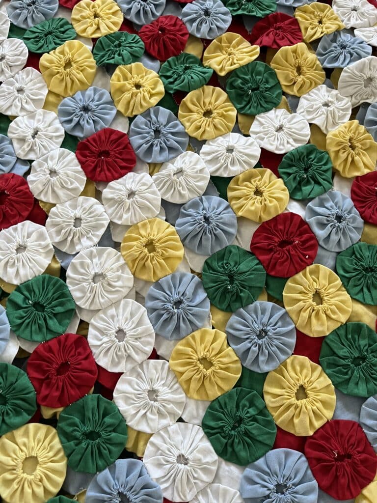 The questions remain: What can be done with these colorful yo-yo squares? Table runners? Maybe. Vests? No.