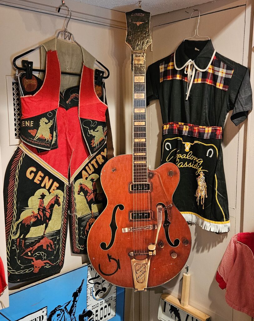 Outfits for would-be young Gene Autrys and Hopalong Cassidys flank a Gretsch 6120 advertising display.