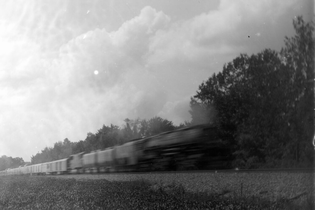 The Union Pacific Big Boy freight train racing through 
the countryside beneath towering summer clouds, 
captured in a long exposure that turns steel 
and motion into a blur of energy.