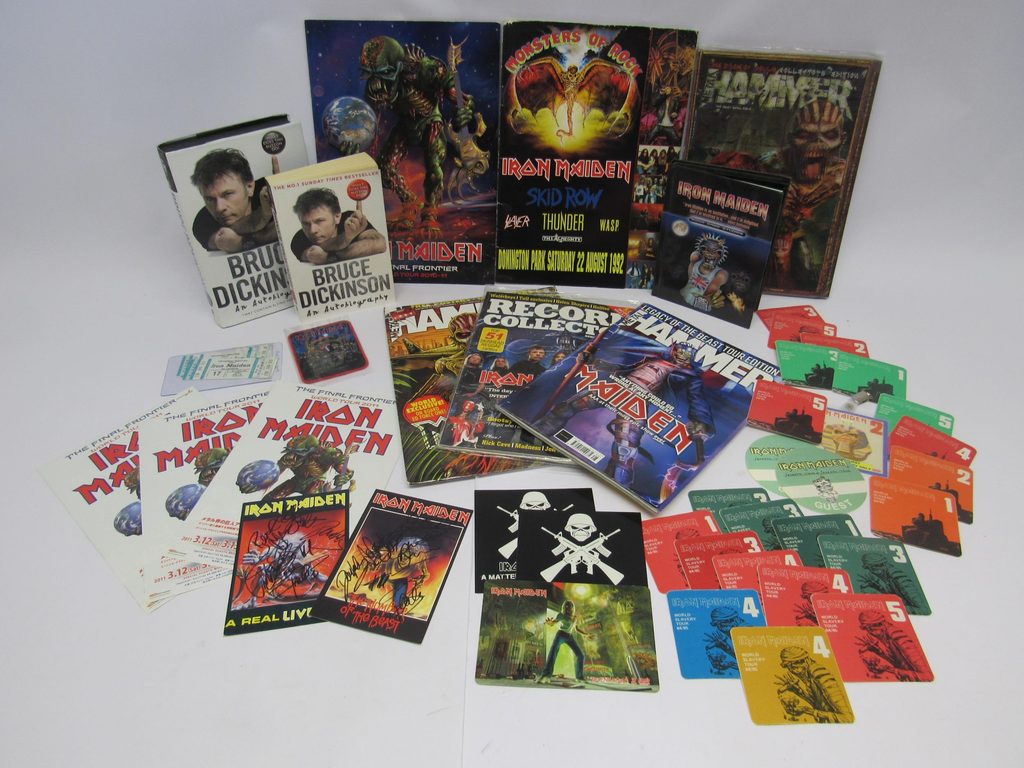 A collection of assorted memorabilia including two signed postcards, aftershow and guest passes, Kiel Auditorium tickets, Monsters of Rock 1992 program, 'The Final Frontier World Tour 2010-11 program, Legacy of The Beast patches, Metal Hammer and Record Collector magazines with Maiden covers, Bruce Dickinson hardback and paperback autobiographies, Rock Case Studies DVD, tour flyers and promotional stickers.
photo: https://www.easyliveauction.com