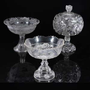 Early American pressed glass EAPG large clear bullseye pattern covered compote candy dish along with two other compoted pedestal bowls; 3pc group. 12"H x 8"W (covered) photo: ripleyauctions.com